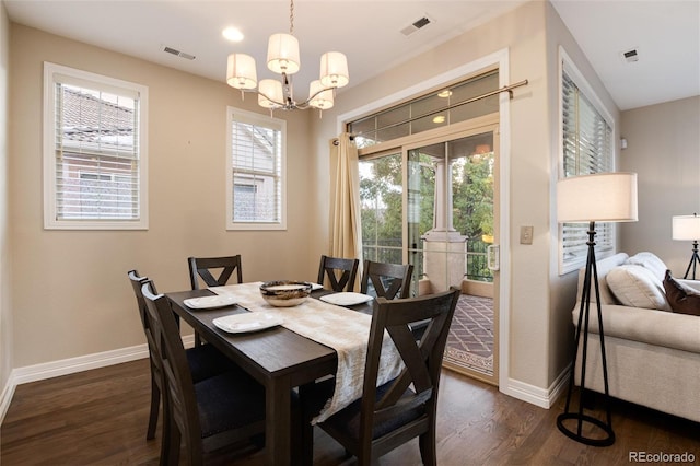 dining area with a wealth of natural light, dark hardwood / wood-style floors, and an inviting chandelier