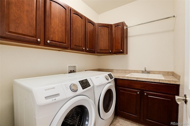 washroom with cabinets, washer and clothes dryer, and sink