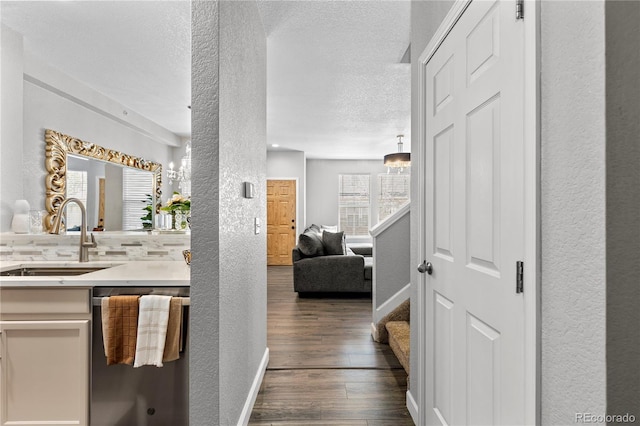 9758 Laredo St Unit 18D, Commerce City, CO 80022 - hallway featuring a textured ceiling, a sink, baseboards, a textured wall, and dark wood-type flooring