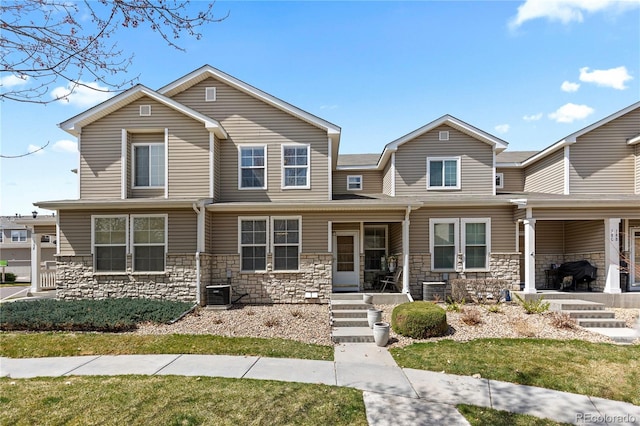 9758 Laredo St Unit 18D, Commerce City, CO 80022 - view of front of home with central AC, a porch, a front lawn, and stone siding