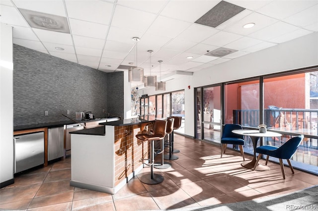 100 Park Ave Unit 2008, Denver, CO 80205 - kitchen with dark countertops, a drop ceiling, refrigerator, a kitchen bar, and dark tile patterned floors