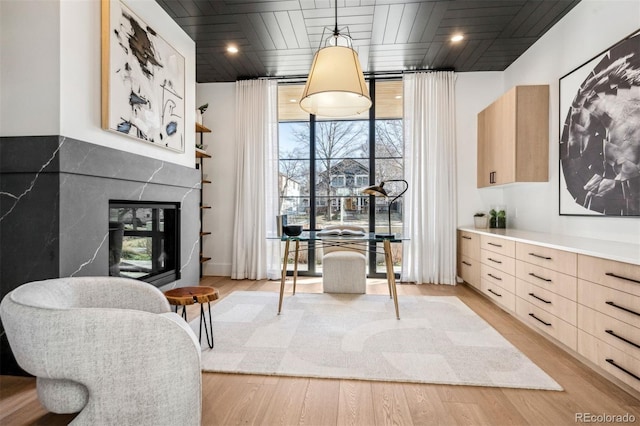 dining space featuring wood ceiling, a fireplace, light wood-type flooring, and a wall of windows