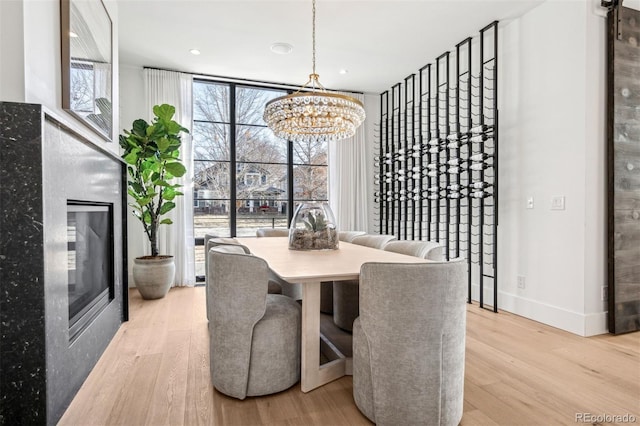 dining room with floor to ceiling windows, a chandelier, and light wood-type flooring