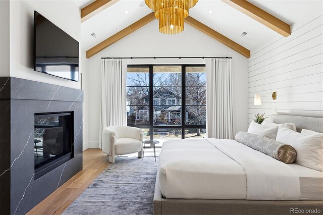 bedroom featuring wood walls, high vaulted ceiling, beamed ceiling, a premium fireplace, and hardwood / wood-style floors