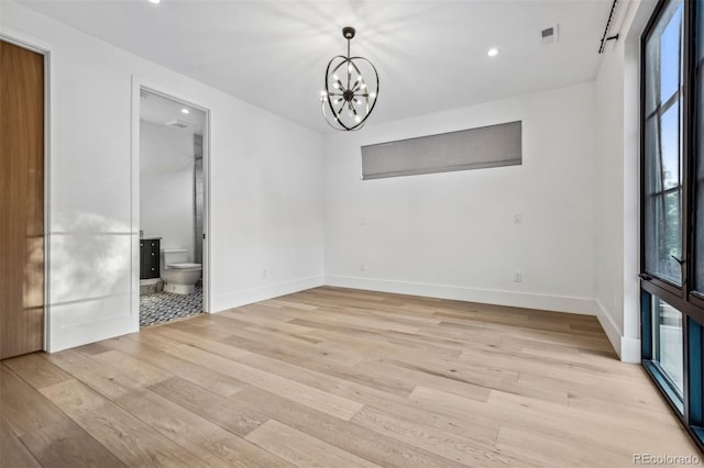 unfurnished dining area featuring a healthy amount of sunlight, a chandelier, and light hardwood / wood-style flooring