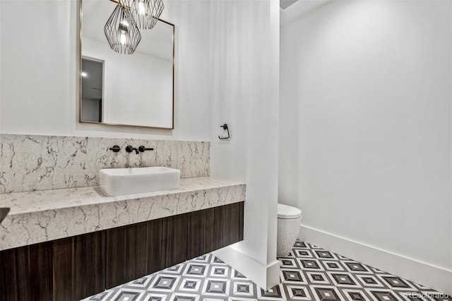 bathroom featuring vanity, toilet, and a notable chandelier