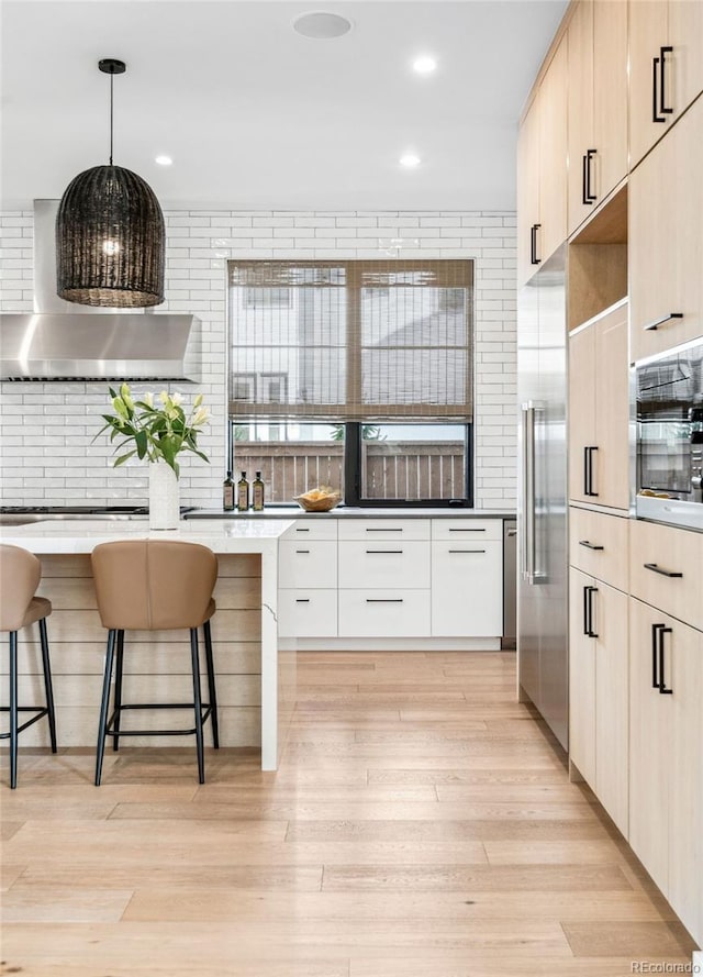 kitchen with pendant lighting, light hardwood / wood-style floors, a breakfast bar, and light brown cabinets