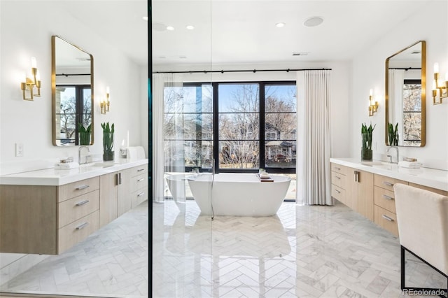 bathroom with a bathing tub, a wealth of natural light, and vanity