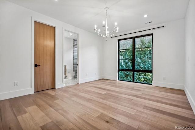 empty room with an inviting chandelier and light hardwood / wood-style floors