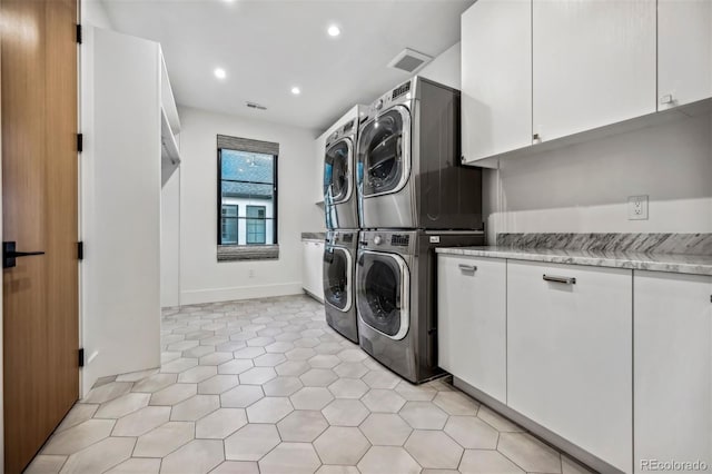 laundry room with cabinets, stacked washer / dryer, and light tile patterned floors