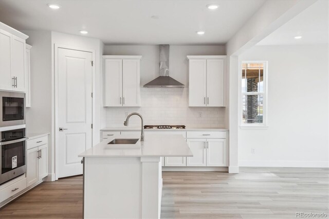 8245 Butte Creek St, Littleton, CO 80125 - kitchen with wall chimney range hood, stainless steel appliances, a sink, light countertops, and light wood-type flooring