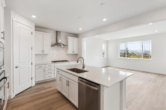 8245 Butte Creek St, Littleton, CO 80125 - kitchen featuring wall chimney exhaust hood, stainless steel dishwasher, a sink, light wood-style flooring, and decorative backsplash