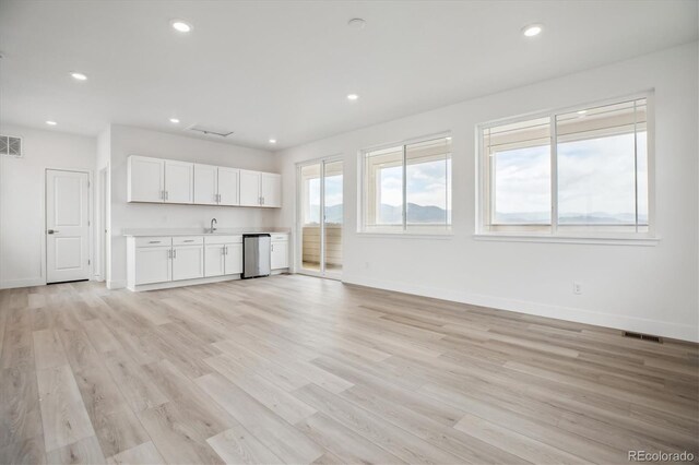 8245 Butte Creek St, Littleton, CO 80125 - unfurnished living room with baseboards, light wood-style flooring, recessed lighting, and wet bar