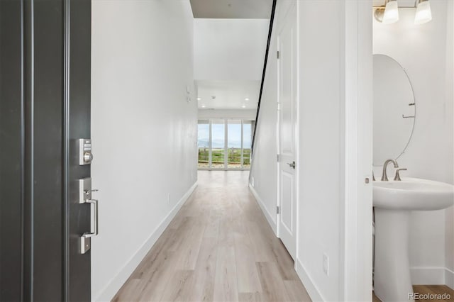 8245 Butte Creek St, Littleton, CO 80125 - corridor featuring light wood-type flooring, baseboards, and a sink