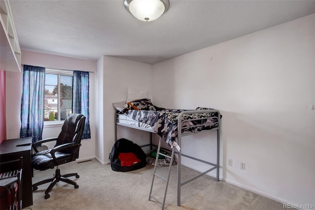 bedroom featuring light colored carpet and a textured ceiling