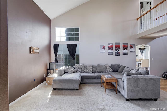 carpeted living room with high vaulted ceiling and a healthy amount of sunlight