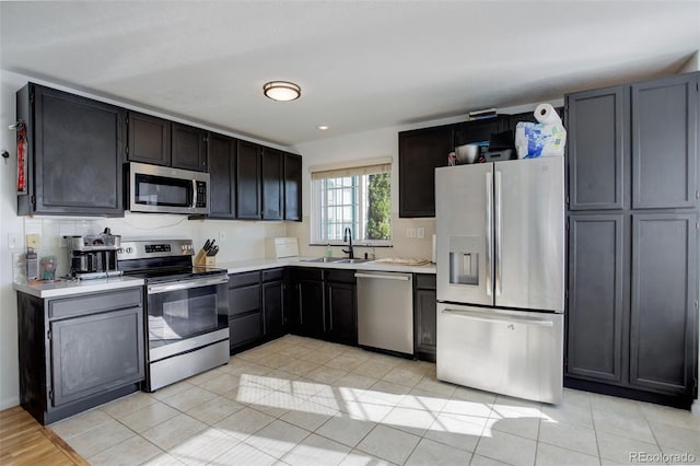 kitchen featuring tasteful backsplash, sink, light tile patterned floors, and appliances with stainless steel finishes