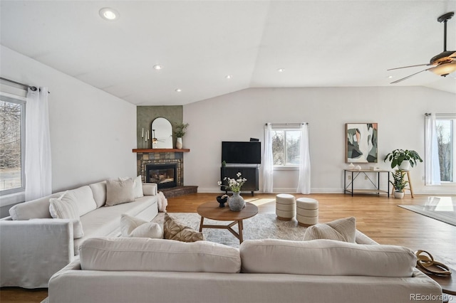 living room featuring vaulted ceiling, wood finished floors, a wealth of natural light, and a large fireplace