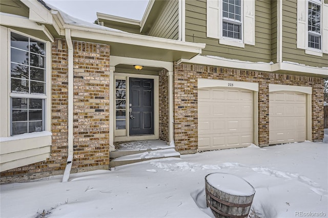 snow covered property entrance with a garage