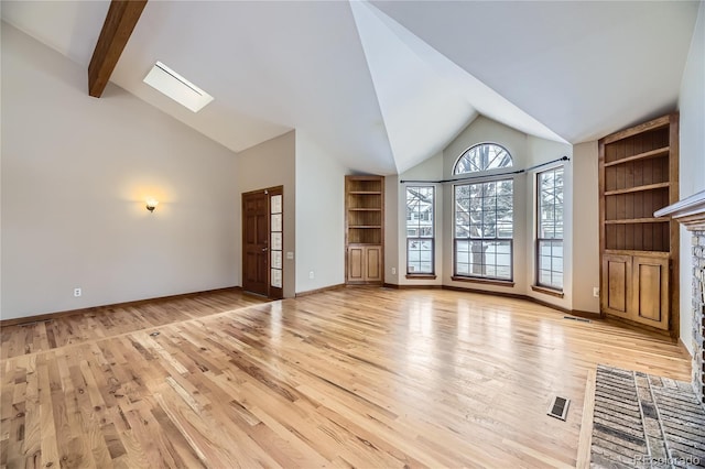 unfurnished living room with a fireplace, light hardwood / wood-style flooring, and vaulted ceiling with skylight