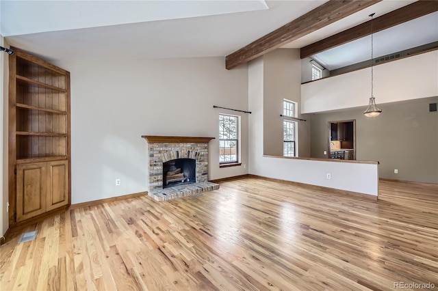 unfurnished living room with lofted ceiling with beams, light wood-type flooring, and a brick fireplace