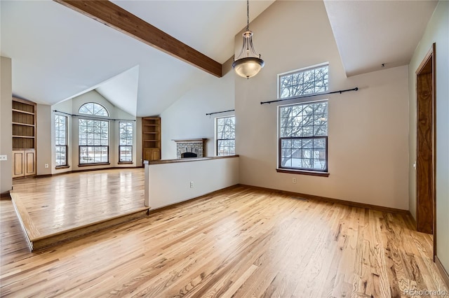 unfurnished living room with built in shelves, light wood-type flooring, a brick fireplace, and a wealth of natural light