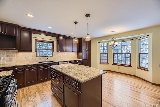 kitchen featuring stainless steel appliances, sink, light hardwood / wood-style flooring, a center island, and hanging light fixtures