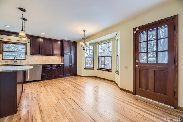 kitchen with light wood-type flooring, backsplash, light stone counters, dishwasher, and hanging light fixtures