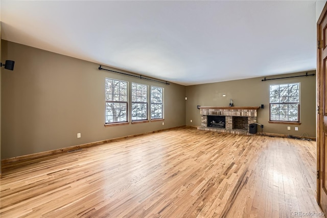 unfurnished living room with plenty of natural light, a fireplace, and light hardwood / wood-style flooring