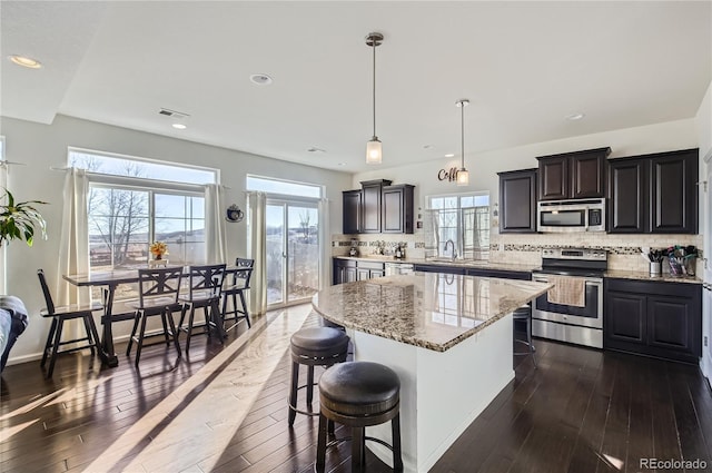 3423 Rosewood Ln, Johnstown, CO 80534 - kitchen featuring dark wood-type flooring, decorative backsplash, a center island, and stainless steel appliances