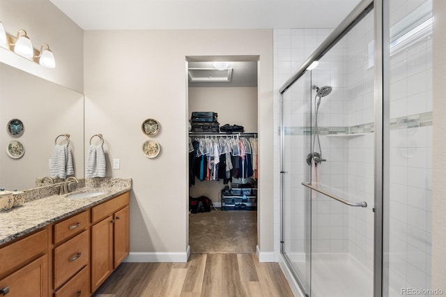 2060 Peralta Loop, Castle Rock, CO 80104 - bathroom with wood finished floors, vanity, a spacious closet, a stall shower, and baseboards