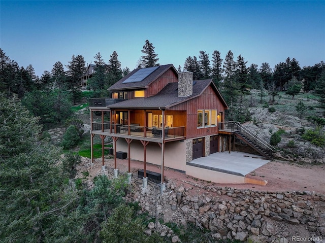 178 Cree Ct, Lyons, CO 80540 - back of house featuring roof mounted solar panels, a garage, a chimney, a patio, and stairs