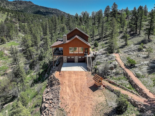 178 Cree Ct, Lyons, CO 80540 - view of front facade featuring driveway, stone siding, a wooded view, a chimney, and stairway