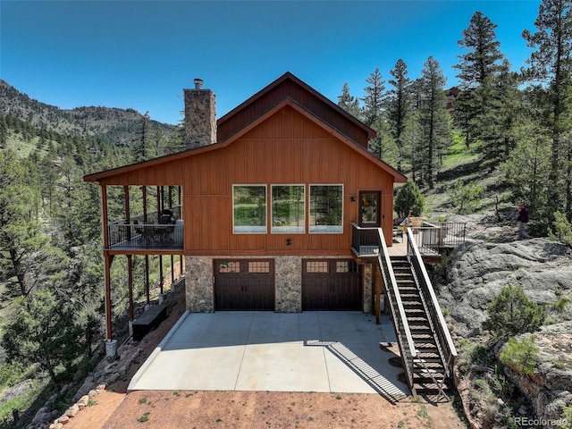178 Cree Ct, Lyons, CO 80540 - chalet / cabin with stairs, a garage, concrete driveway, stone siding, and a chimney