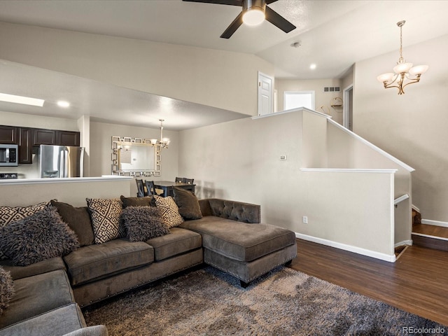 living room with dark wood-type flooring, ceiling fan with notable chandelier, and vaulted ceiling