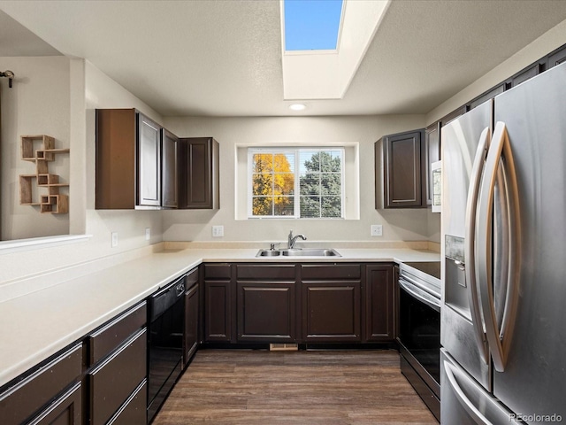 kitchen with dark hardwood / wood-style flooring, appliances with stainless steel finishes, a skylight, dark brown cabinetry, and sink