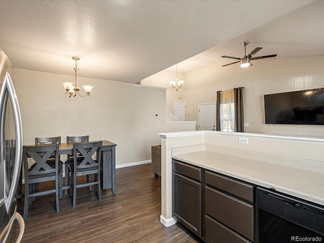 kitchen featuring dark hardwood / wood-style flooring, stainless steel fridge, ceiling fan with notable chandelier, and pendant lighting