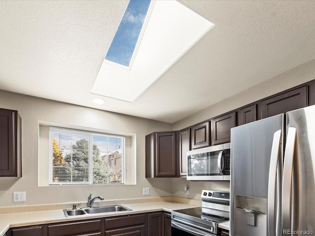 kitchen featuring dark brown cabinets, stainless steel appliances, sink, and a skylight