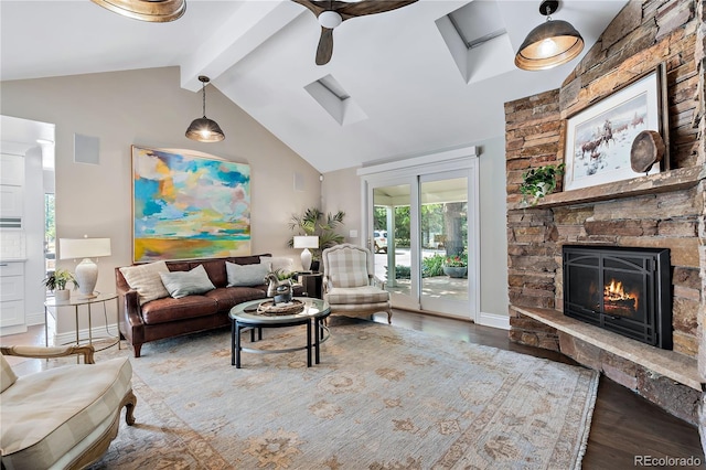 living room featuring hardwood / wood-style floors, a fireplace, vaulted ceiling with skylight, and ceiling fan