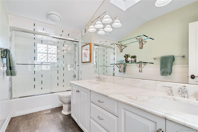 full bathroom with vanity, lofted ceiling with skylight, shower / bath combination with glass door, and toilet