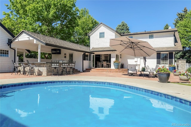 view of pool with a patio and a bar