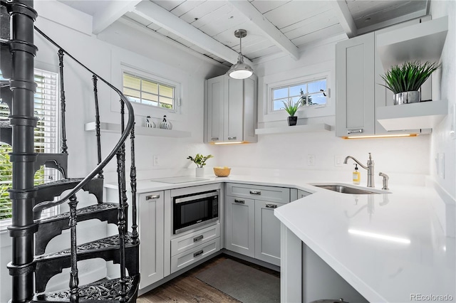 kitchen featuring dark hardwood / wood-style floors, stainless steel microwave, decorative light fixtures, sink, and beam ceiling