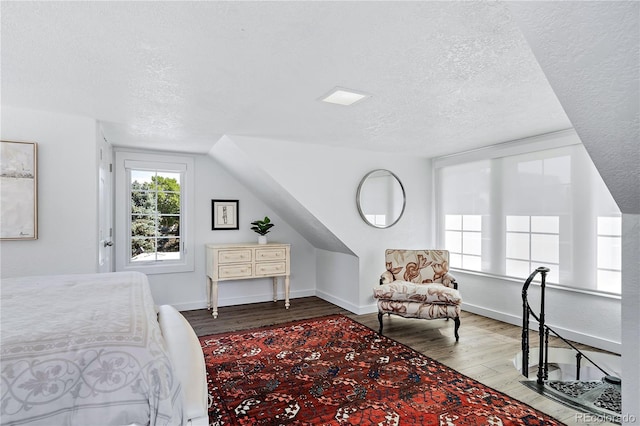 bedroom with wood-type flooring, lofted ceiling, and a textured ceiling