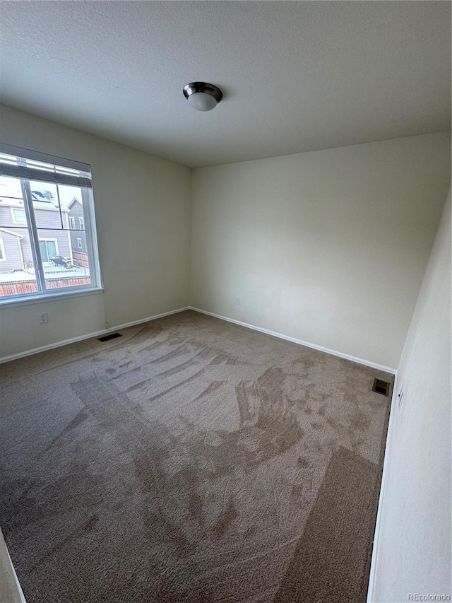 carpeted empty room with a textured ceiling