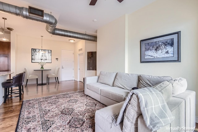 living area featuring ceiling fan, visible vents, baseboards, and wood finished floors