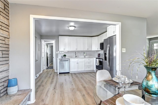 2921 E Colorado Ave, Denver, CO 80210 - kitchen featuring tasteful backsplash, stainless steel appliances, light countertops, light wood-type flooring, and white cabinetry