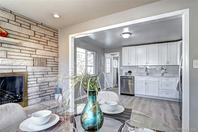 2921 E Colorado Ave, Denver, CO 80210 - kitchen with light wood finished floors, tasteful backsplash, white cabinets, light countertops, and stainless steel dishwasher