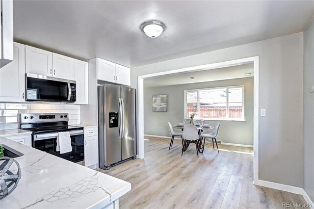 2921 E Colorado Ave, Denver, CO 80210 - kitchen with light wood finished floors, white cabinets, decorative backsplash, appliances with stainless steel finishes, and light stone counters