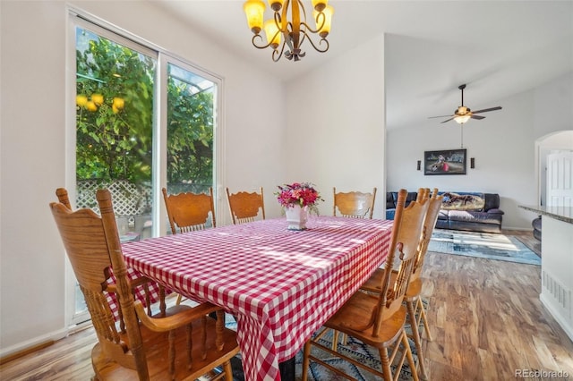 dining space with lofted ceiling, ceiling fan with notable chandelier, and light hardwood / wood-style flooring