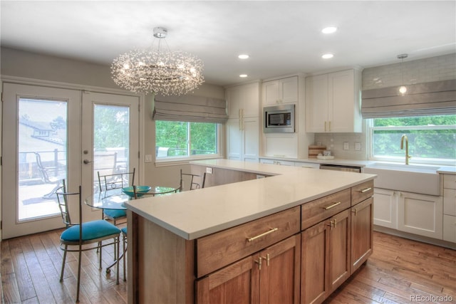 8140 S Storm King Peak, Littleton, CO 80127 - kitchen with stainless steel microwave, light countertops, light wood finished floors, a center island, and decorative backsplash